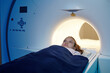 Adorable child lying on table while moving into mri scan machine before medical examination