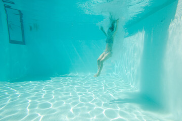 Woman swimming underwater in pool