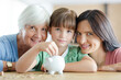© KOTO - Three generations of women filling piggy bank