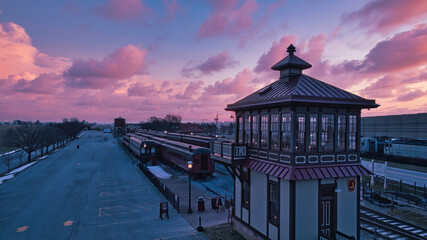 Wall Mural - Sunrise With Blue, Red Sky and Clouds Looking Over a Train Station and Yard