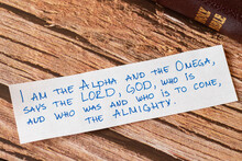 God Jesus Christ Is The I AM, Alpha And Omega, First And Last, The LORD Almighty. Closeup Of Handwritten Message On Wooden Background With Closed Bible. Biblical Concept Book Of Revelation.