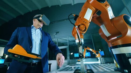 Wall Mural - robotic arm is being operated by a male researcher with vr-device