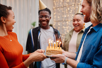 Poster - Side view portrait of young African-American woman holding birthday cake at rooftop party with friends