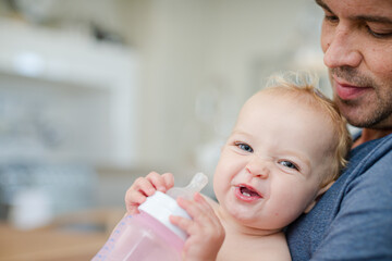 Father feeding baby in kitchen