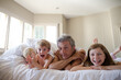 © KOTO - Father and children relaxing on bed
