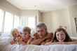 © KOTO - Father and children relaxing on bed