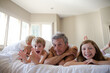 © KOTO - Father and children relaxing on bed