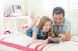 Father and daughter using digital tablet on bed