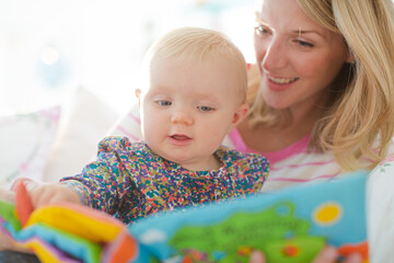 mother reading to baby girl on sofa
