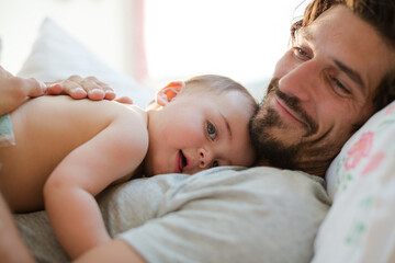 Father laying with baby boy on bed