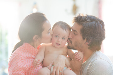 Wall Mural - Parents kissing baby boy's cheeks