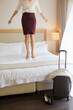 © KOTO - Businesswoman jumping on bed in hotel room