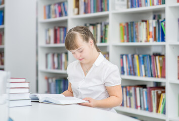 Poster - Smart young girl with syndrome down reads a book at library. Education for disabled children concept