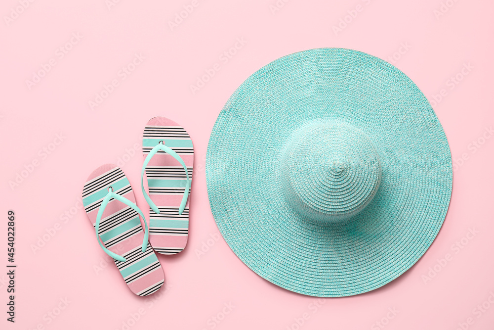 Stylish hat and flip-flops on color background