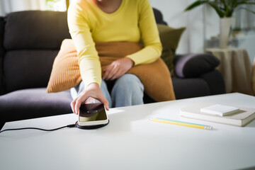 Wall Mural - Charging mobile phone battery with wireless charging device in the table. Smartphone charging on a charging pad. Mobile phone near wireless charger Modern lifestyle technology concept.