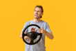 © Pixel-Shot - Angry young man with steering wheel on color background