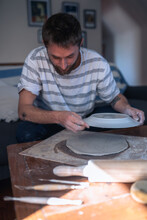 The Process Of Making Ceramic Crockery. Man Making Sure Plate Is Round