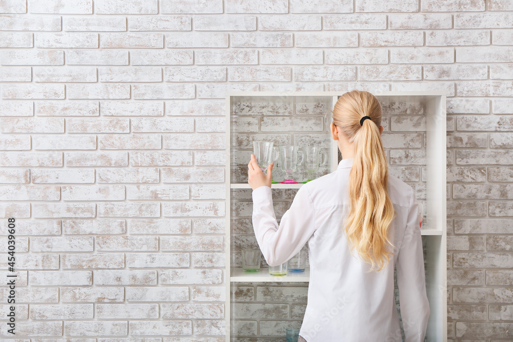 Woman with empty stylish glass near brick wall