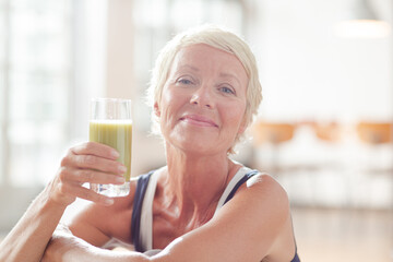 Older woman drinking juice on exercise mat