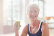 Older woman drinking juice on exercise mat