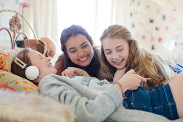 Canvas Print - Three teenage girls listening to music on bed in bedroom