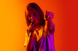 © Lustre Art Group  - Cropped portrait of young beautiful caucasian girl singing with microphone on gradient yellow red background