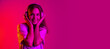 © Lustre Art Group  - Beautiful young caucasian girl listening to music in headphones isolated on pink background in neon