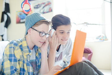 Canvas Print - Two teenage boys sharing laptop and headphones in room