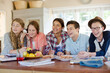 © KOTO - Group of smiling teenagers gathered around table in dining room
