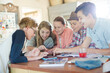 © KOTO - Group of teenagers using together digital tablet at table in kitchen