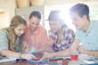 © KOTO - Group of teenagers using together digital tablet at table in kitchen