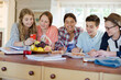 © KOTO - Group of smiling teenagers gathered around table in dining room
