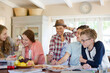 © KOTO - Group of smiling teenagers gathered around table in dining room