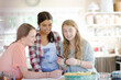 © KOTO - Three teenage girls looking at photograph while sitting at table