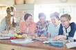 © KOTO - Group of smiling teenagers gathered around table in dining room