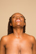 © Phiwo Ndlovu/Cultura Creative - Studio portrait of smiling shirtless woman with braided hair
