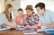 © KOTO - Group of teenagers using together digital tablet at table in kitchen