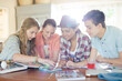 © KOTO - Group of teenagers using together digital tablet at table in kitchen