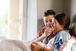© KOTO - Teenage couple lying in bed and eating popcorn
