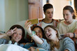 © KOTO - Group of teenagers taking selfie on sofa in living room