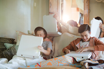 Wall Mural - Group of teenagers opening pizza boxes on sofa in living room