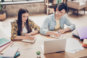 Sticker - Portrait of two attractive busy cheery smart learners writing test exam watching video at library loft industrial interior indoors