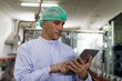 © amorn - Male worker wearing hairnet holding and checking goods or product of Basil seed with fruit on the conveyor belt in the beverage factory before shipment. Inspection quality control