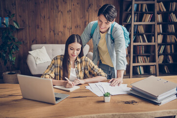 Poster - Portrait of two handsome beautiful focused cheery pupils writing essay help at library loft industrial interior indoors