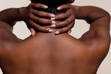 Rear view of shirtlesss woman with hands on her neck