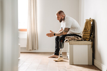 Wall Mural - White military man with prosthesis siting on bench at home