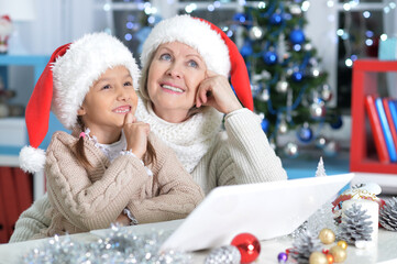 Canvas Print - Portrait of grandmother and her granddaughter using laptop