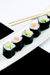 Poster - Closeup of sushi rolls on a white plate with wooden sticks