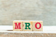 Alphabet letter block in word MRO (Abbreviation of Maintenance, repair and overhaul or Maintenance, Repair and Operations) on wood background