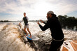 © fesenko - one-armed man riding on wakeboard and instructor explains how to do it right